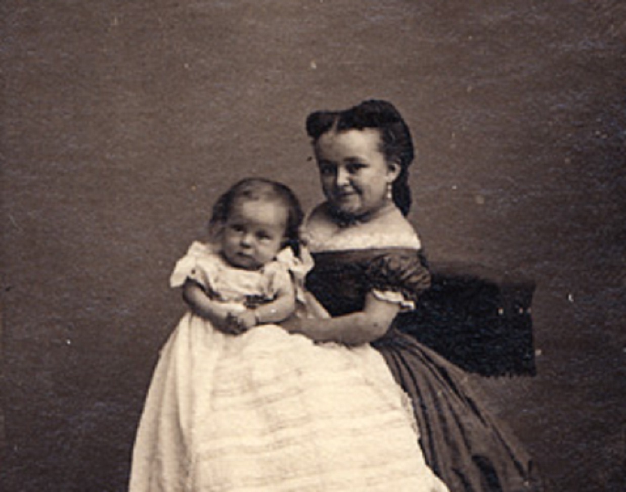 Lavinia Warren Stratton is holding a baby in her hands and looking at camera - 1860s