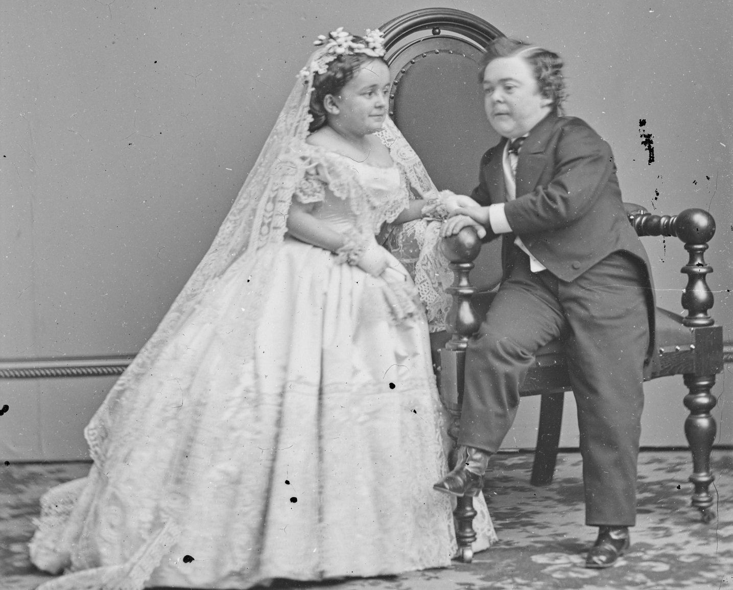 B&W photo of Charles and Lavinia Stratton holding hands and seating on the chair - 1860s