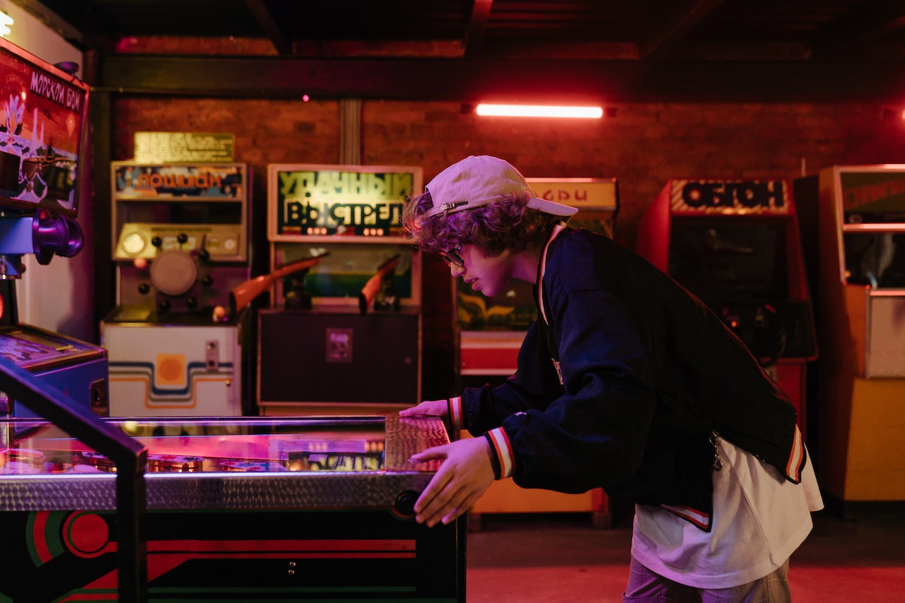 Young man wearing black jacket and hat is playing the arcade game.
