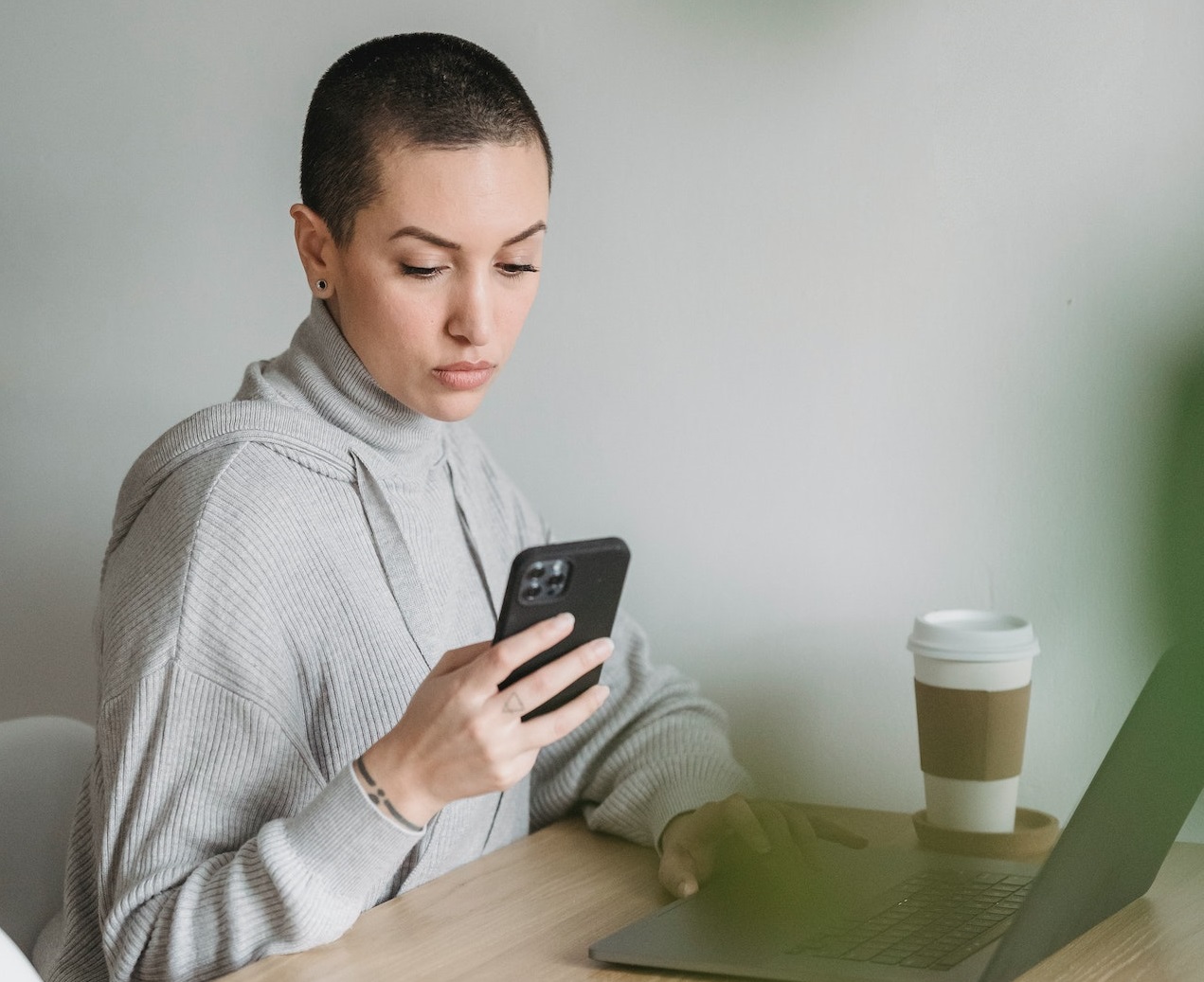 Young woman is seating on her desk and texting from phone.