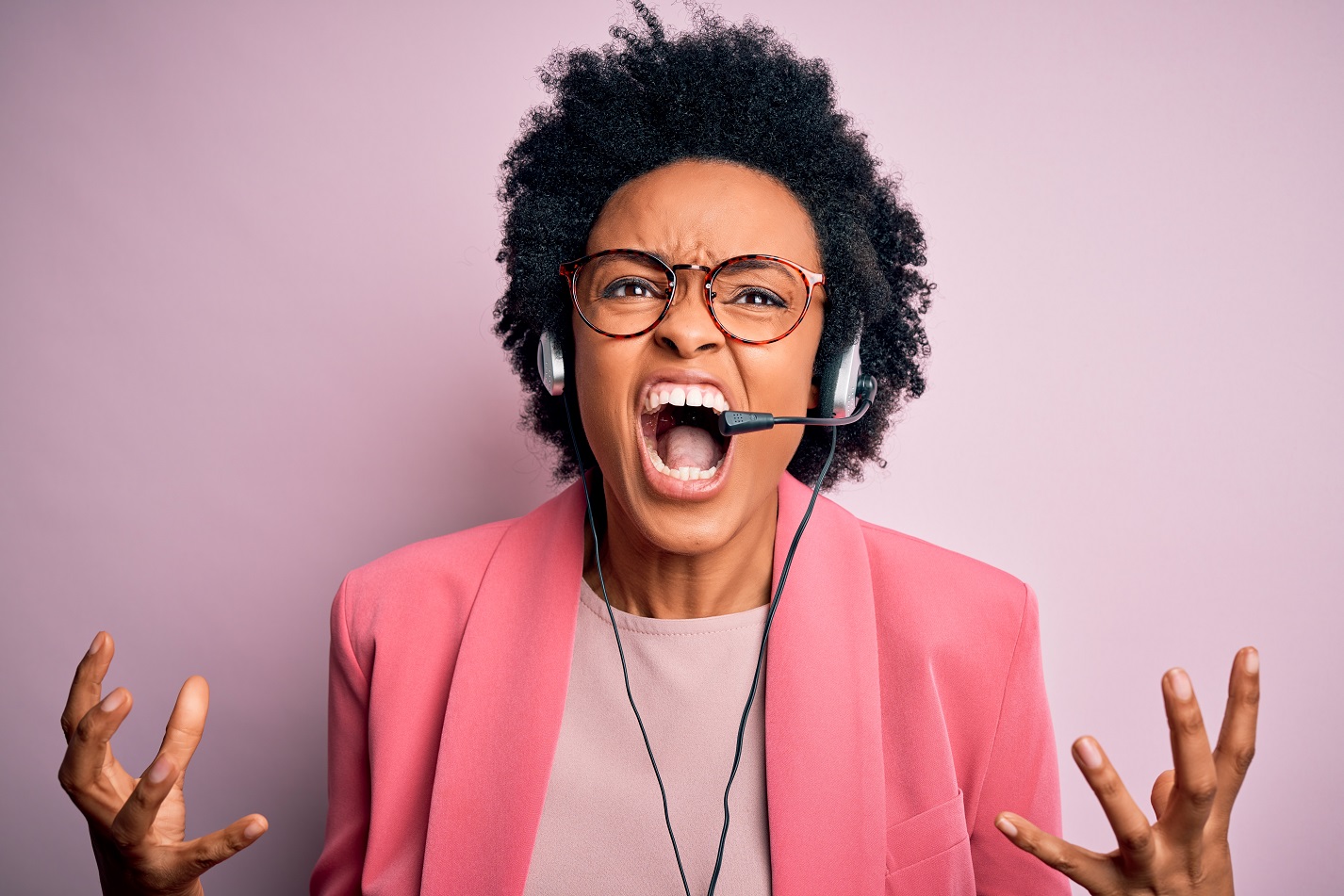 Young female call center operator is yelling on her headphones.