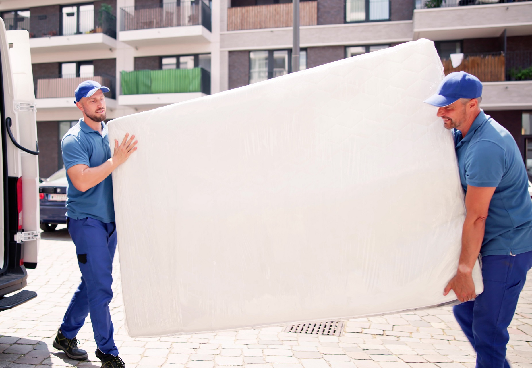 Movers are transporting a new mattress with their van.