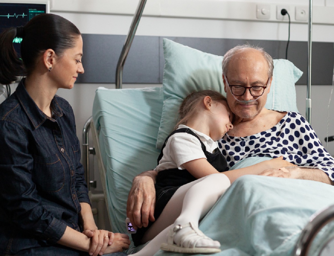 Man laying in hospital bed with people next to him.