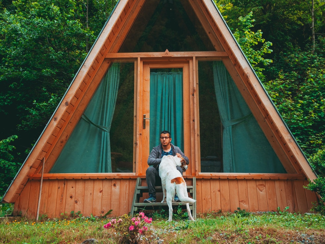 Man is seating in front of a cabin.