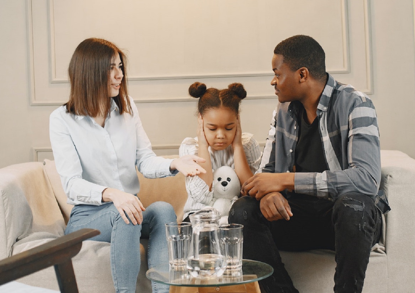 Girl is covering her ears and talking with her parents.