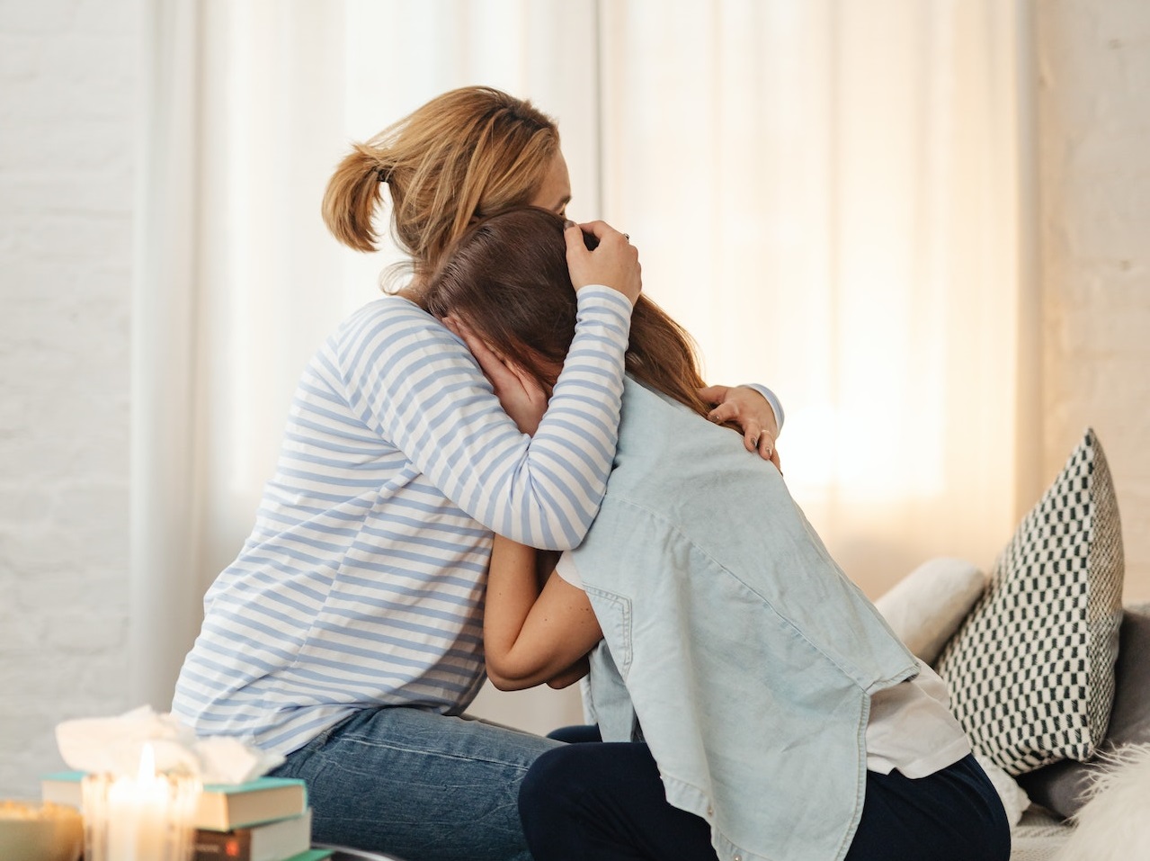 Mother is hugging her daughter who is crying.
