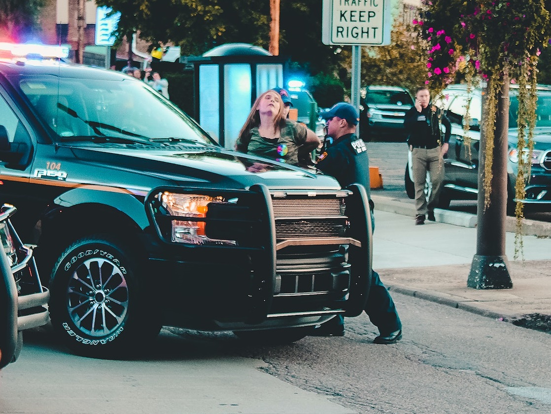 Young woman is getting arrested by the police .