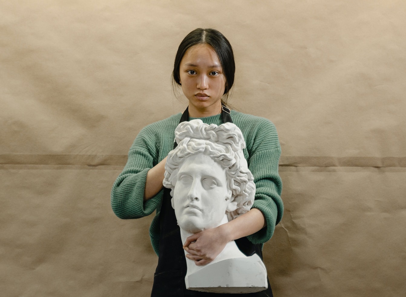 Young woman is holding a white head statue in hands.