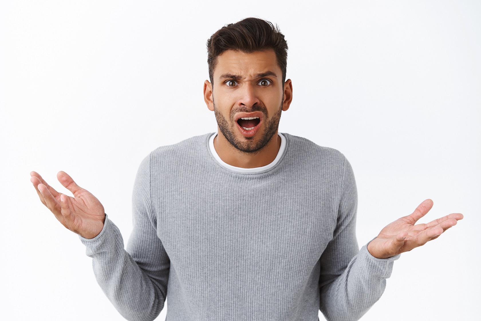 Young bearded man is looking surprised with hands up.