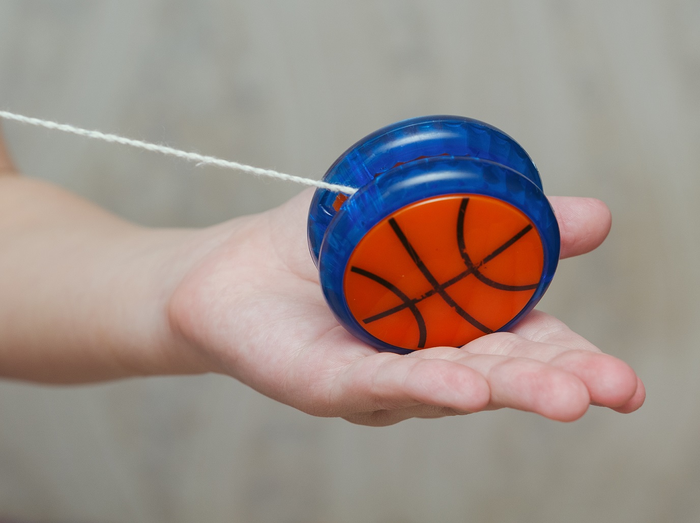 Blue and orange yo-yo toy in the hands of a man.
