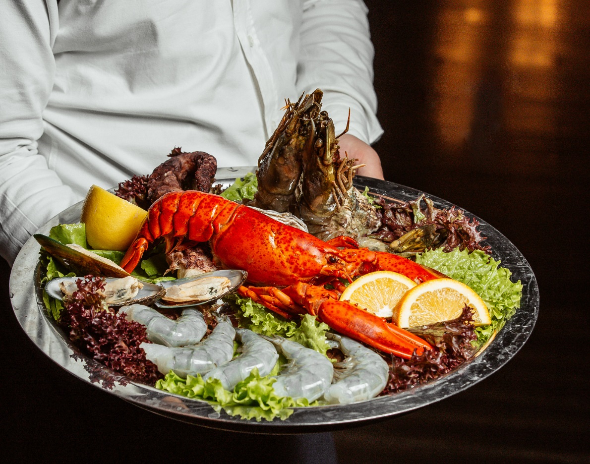 Waiter holding seafood platter with lobster king.