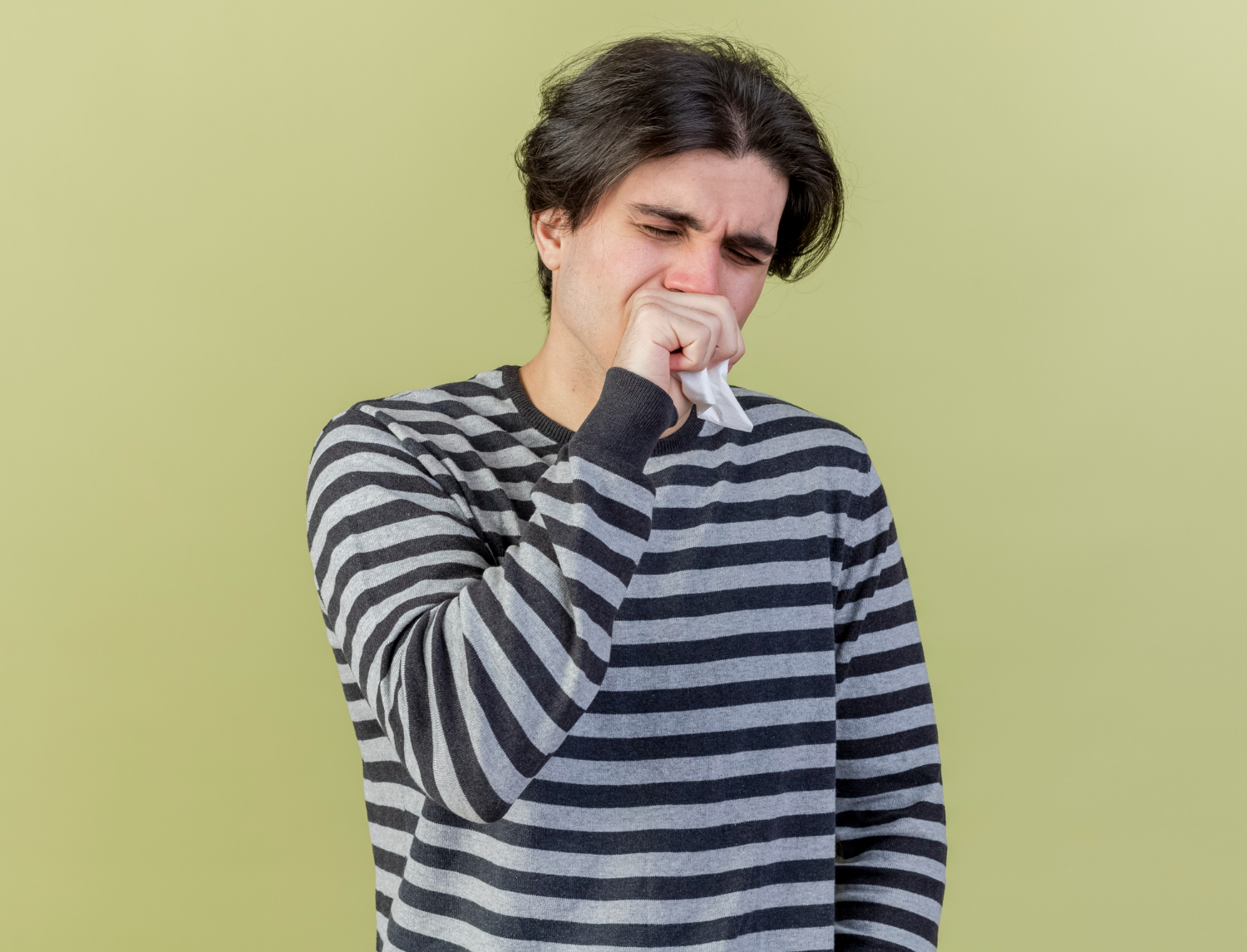 Young man is coughing and covering his mouth with his hand.