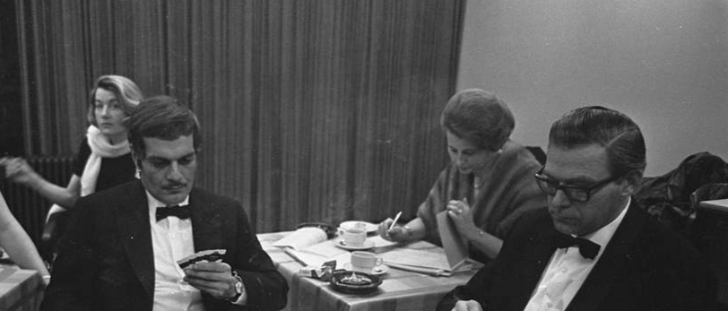 Bridge demonstration by Omar Sharif sitting at table in suit