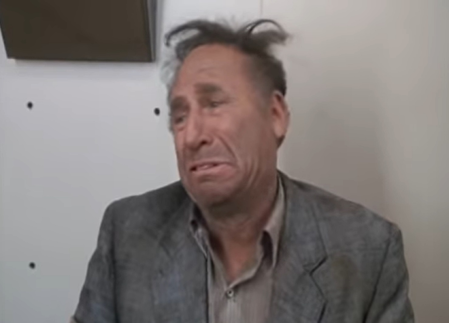 Screenshot: Mel Brooks with messy hair is looking at side with sad face  - from Life Stinks (1991)