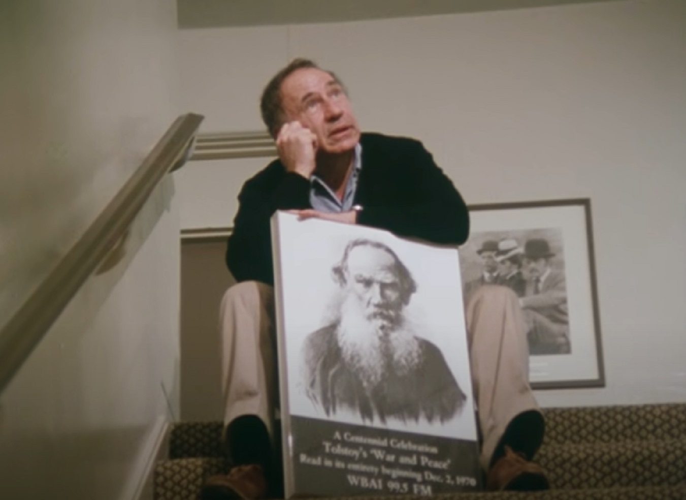 Screenshot: Mel Brooks is seating on stairs and holding a picture - from Mel Brooks-Unwrapped (2018)