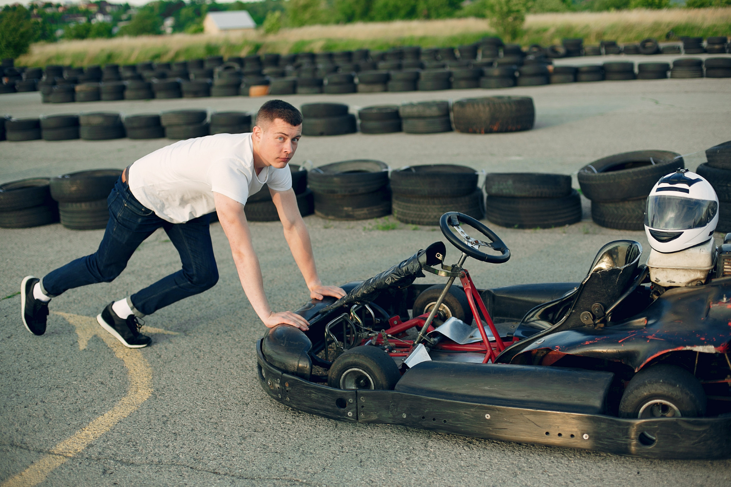 Young man is pushing a karting on karting circuit.