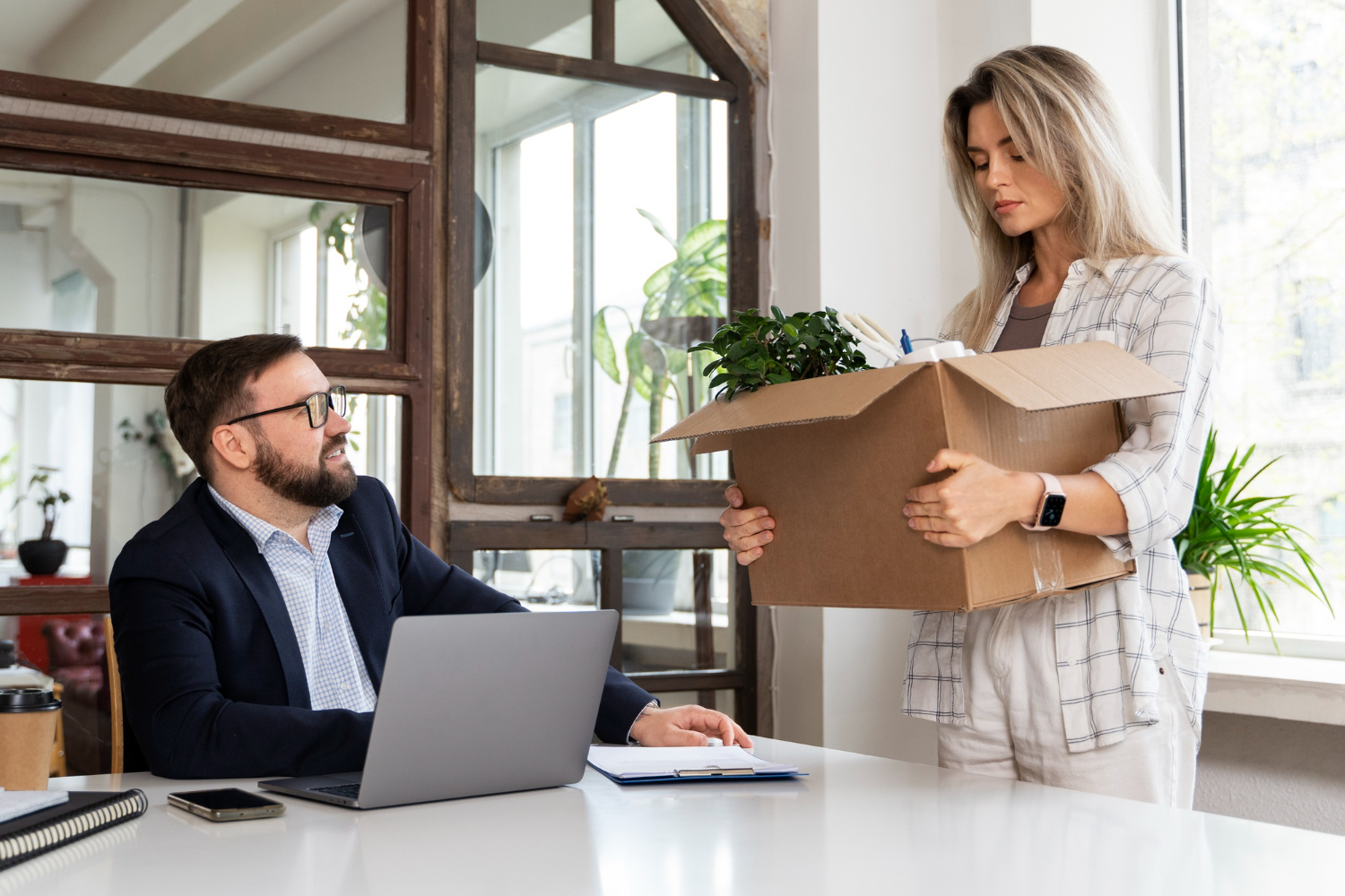 Young woman is holding a box and talking with man in suit - getting fired.
