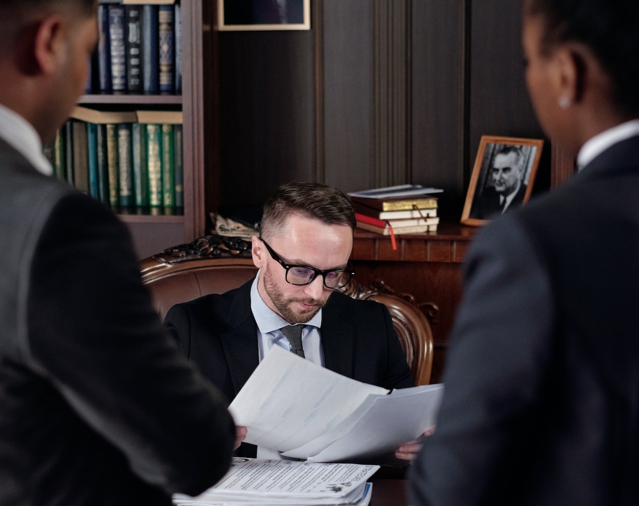 Two lawyers are standing in front of a judge seating on the desk.