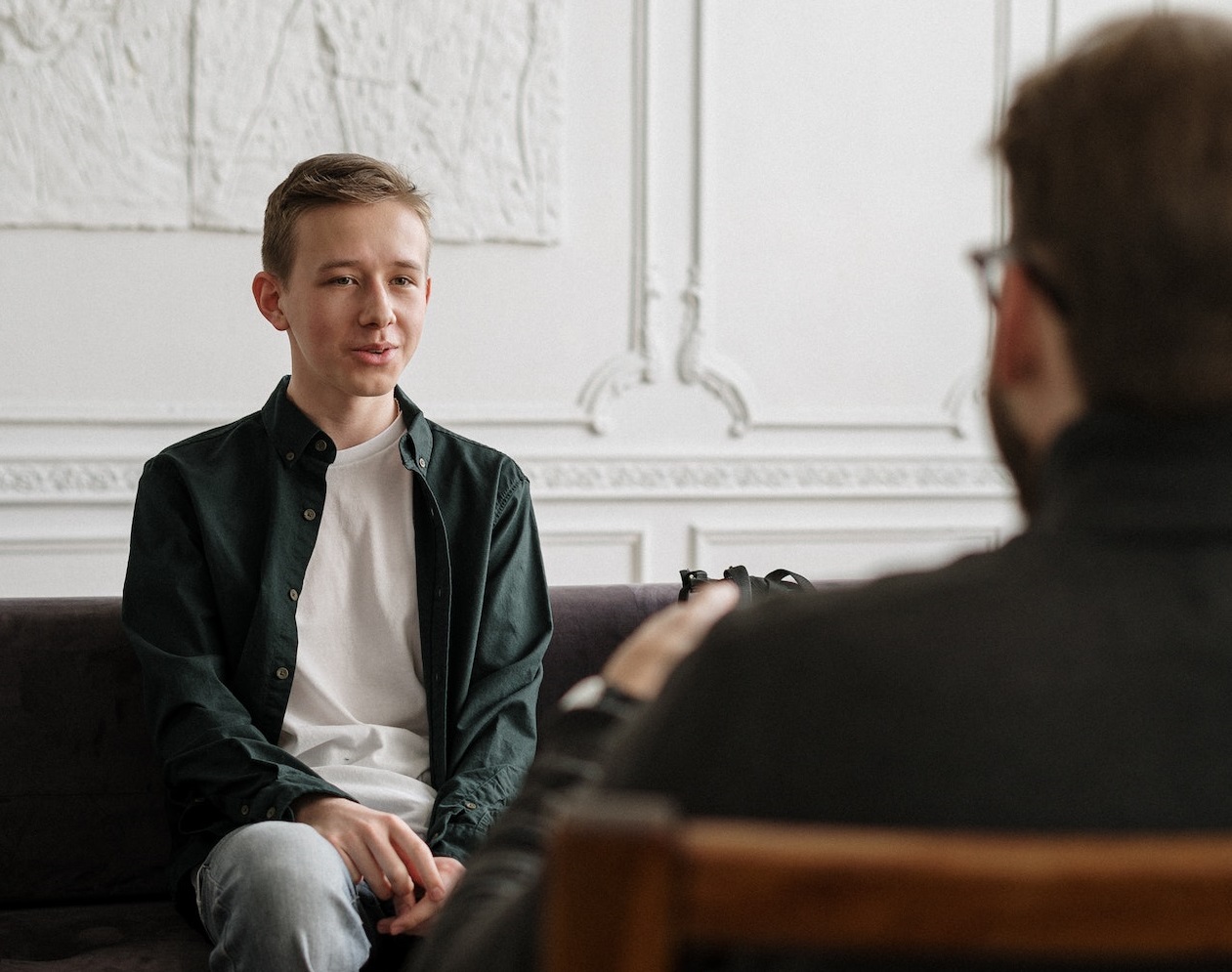 Young man is talking in office with other man and smiling.