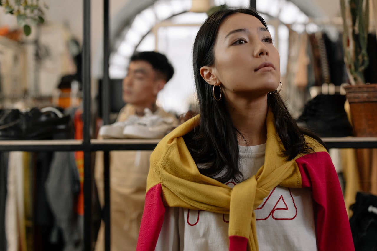 Young woman is standing and looking at clothes in the store.