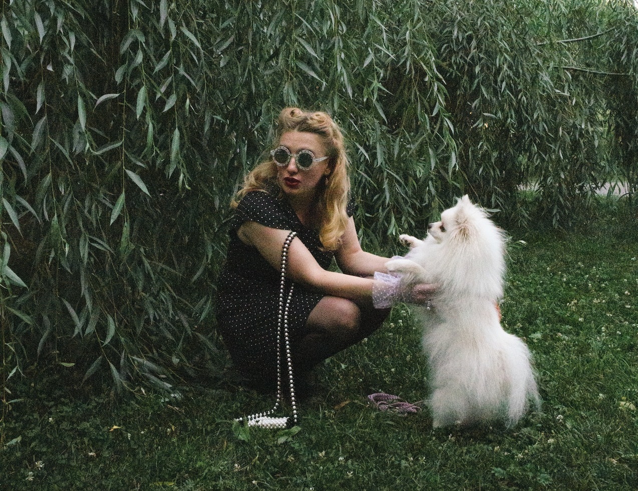 Woman is playing with her white dog in a park.