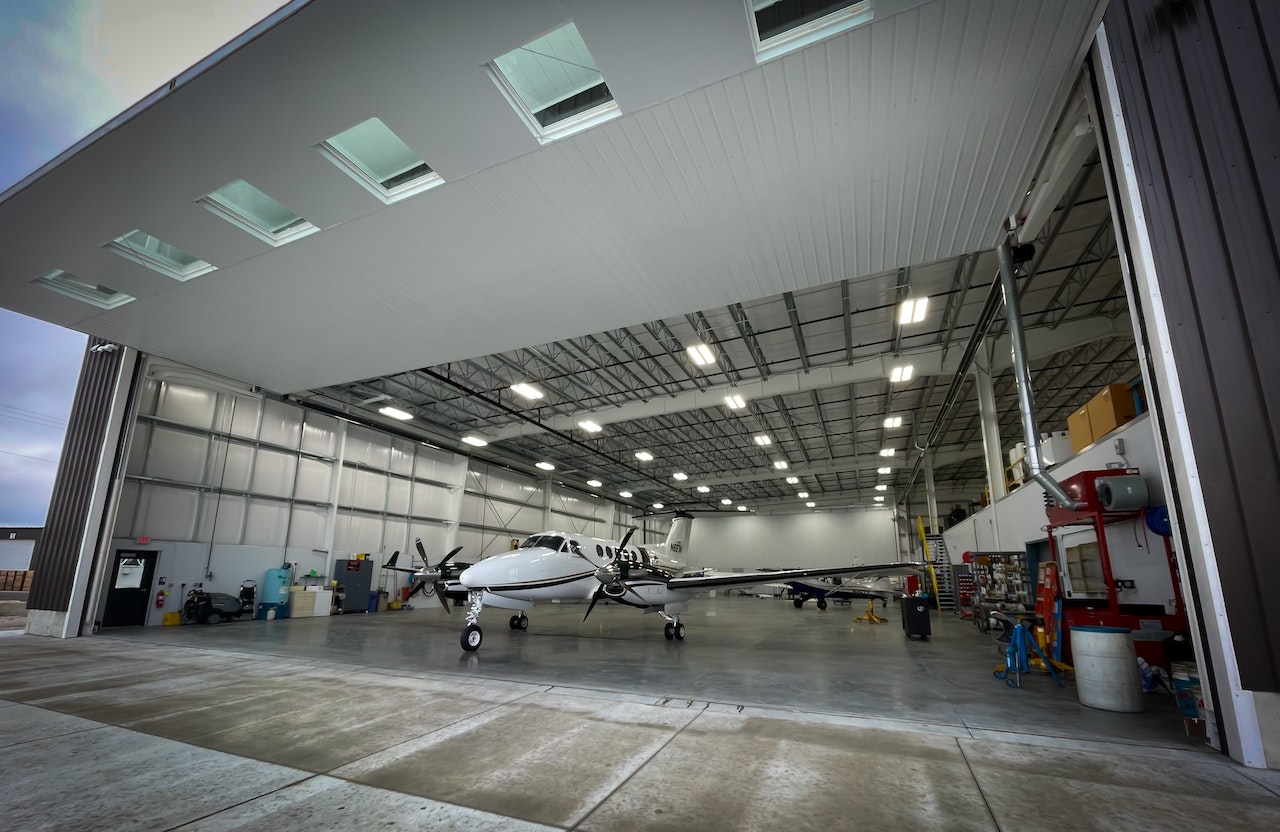 Light white plane is parked in a hangar.