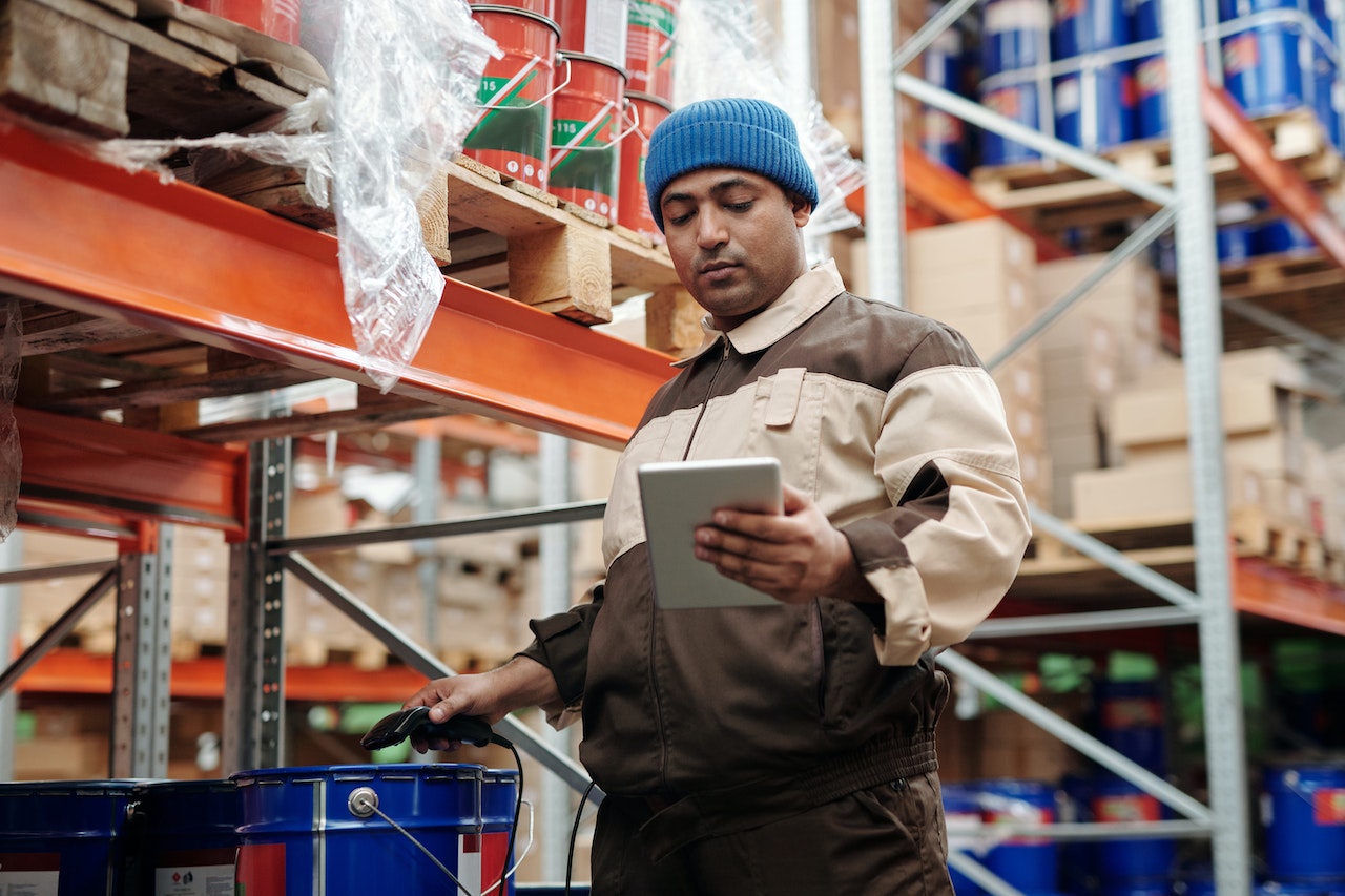 Man working at warehouse is scanning the cans with paint.