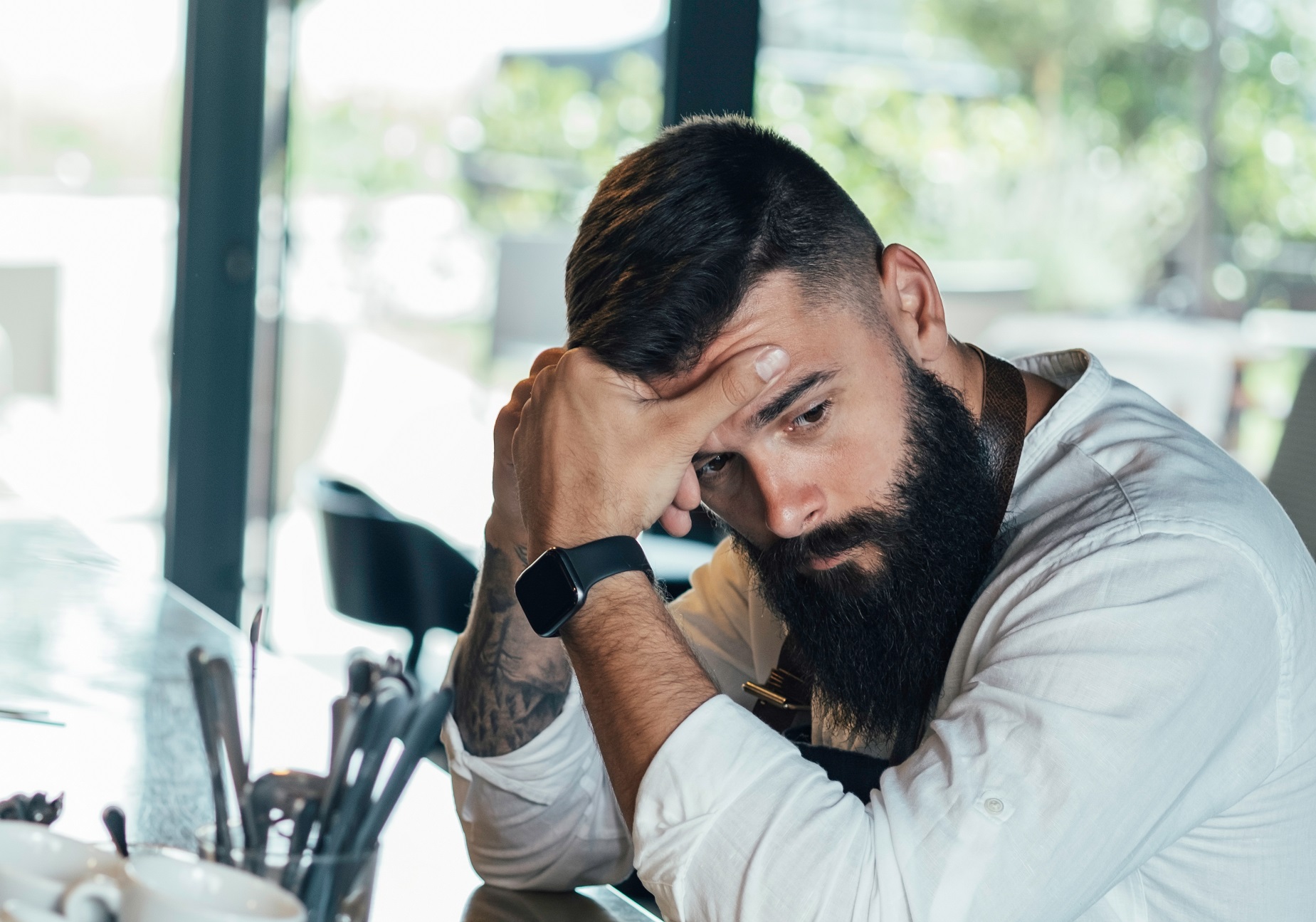 Young bearded man is looking sad ,seating at bar.