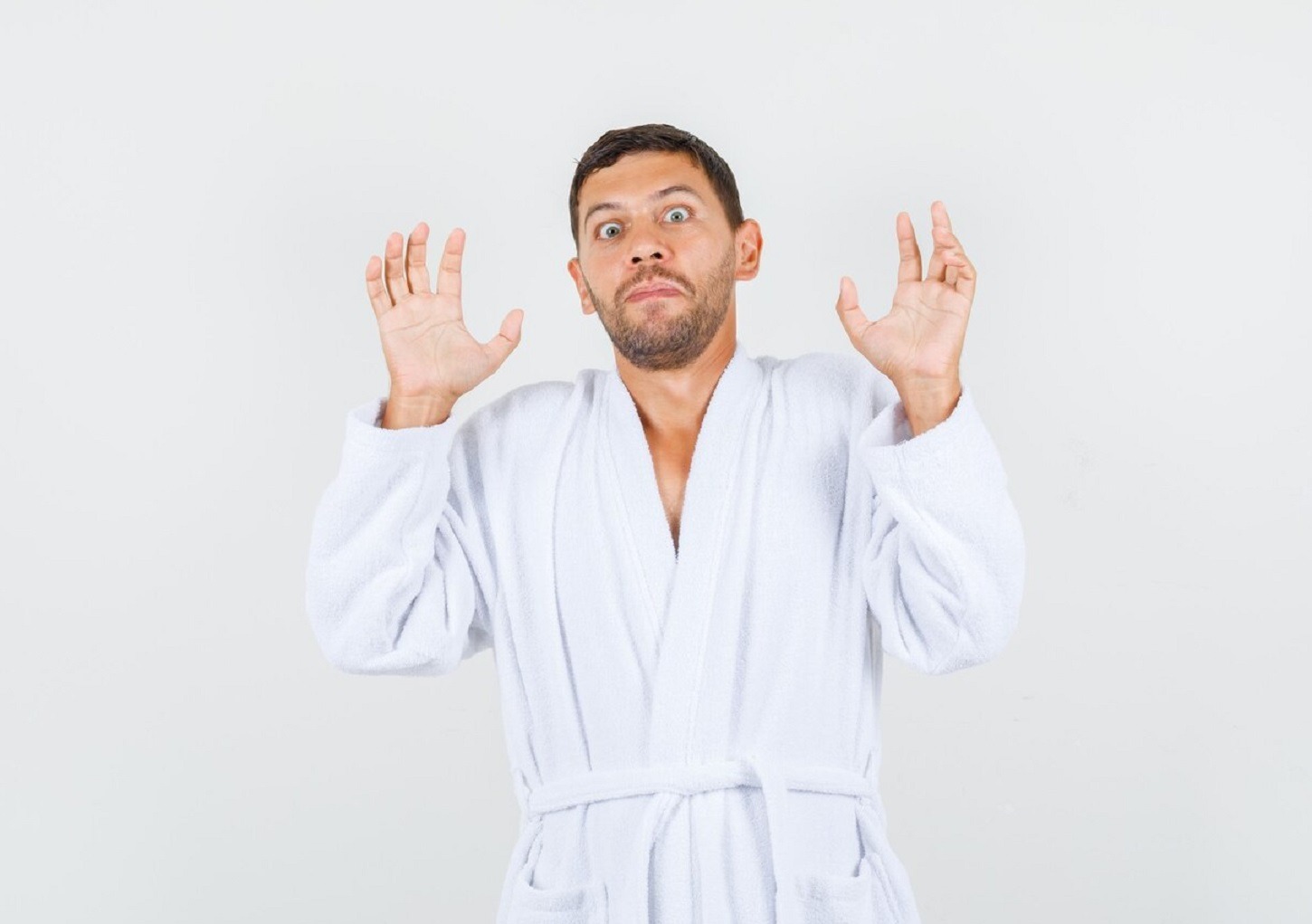 Young man is looking surprised at camera with arms up.