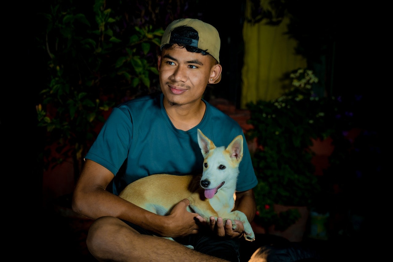 Young man is holding a small dog in his hands.