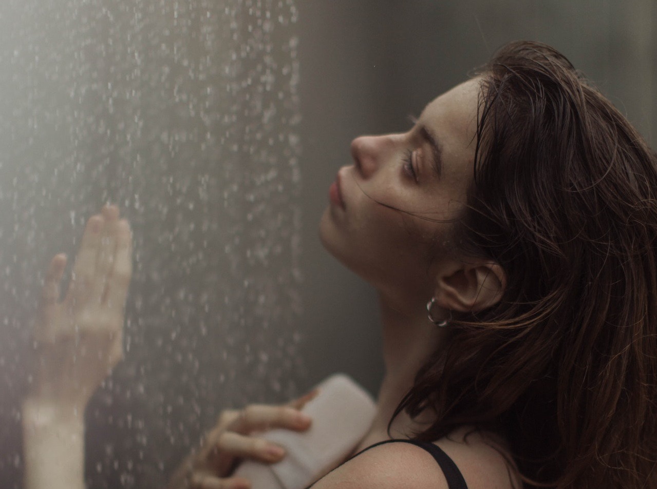 Young woman with long hair is showering.