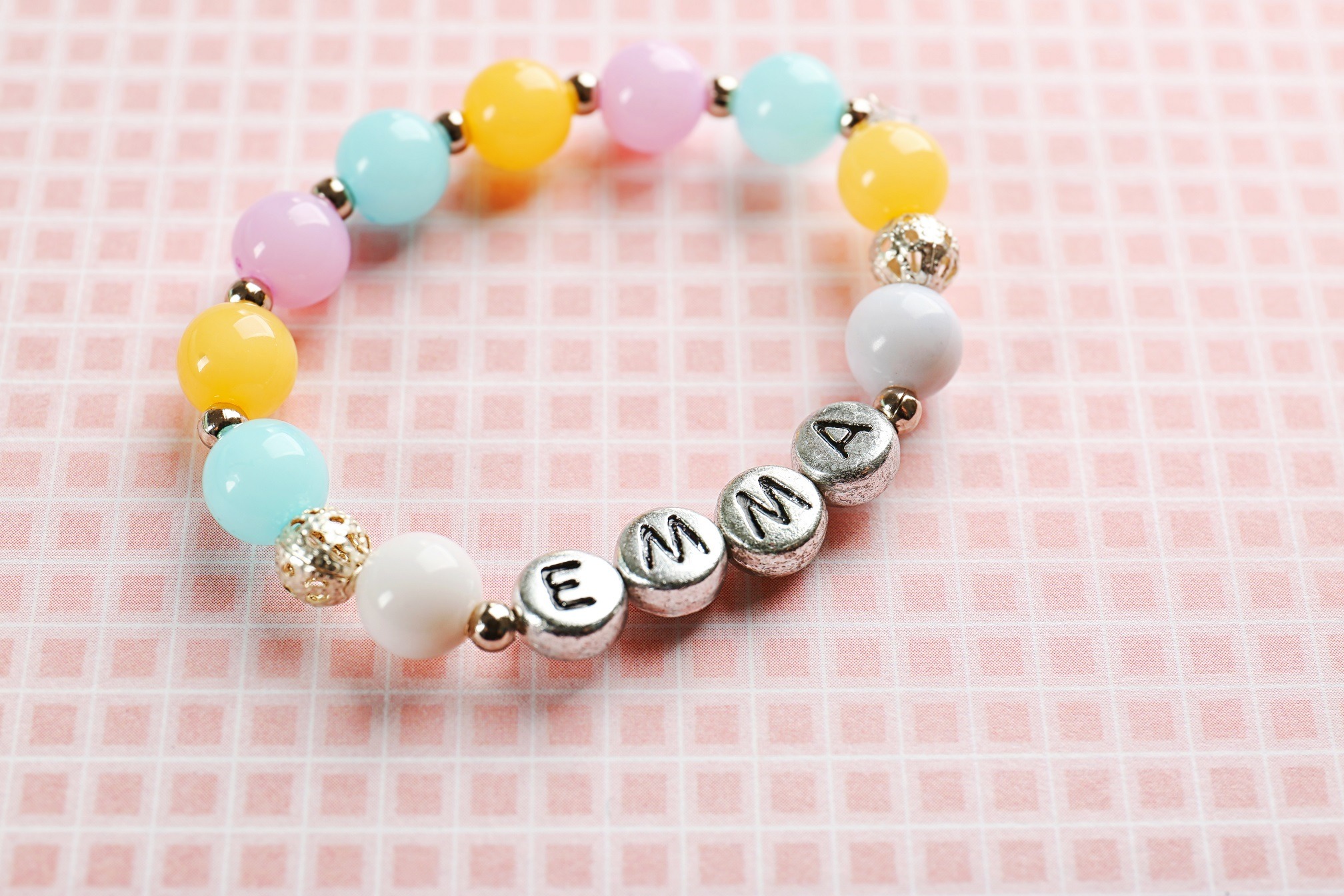 Bracelet with different colors and name EMMA is standing on the table.