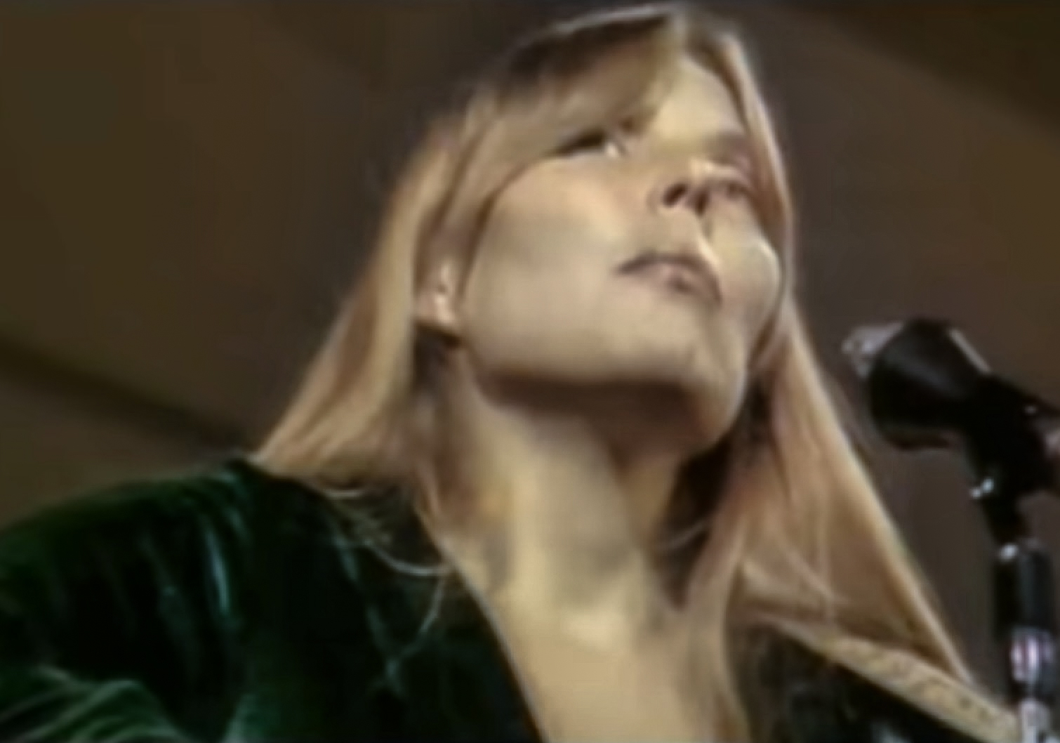 Screenshot: Joni Mitchell wearing green dress is looking at side - from Joni Mitchell: A Woman of Heart and Mind (2003)
