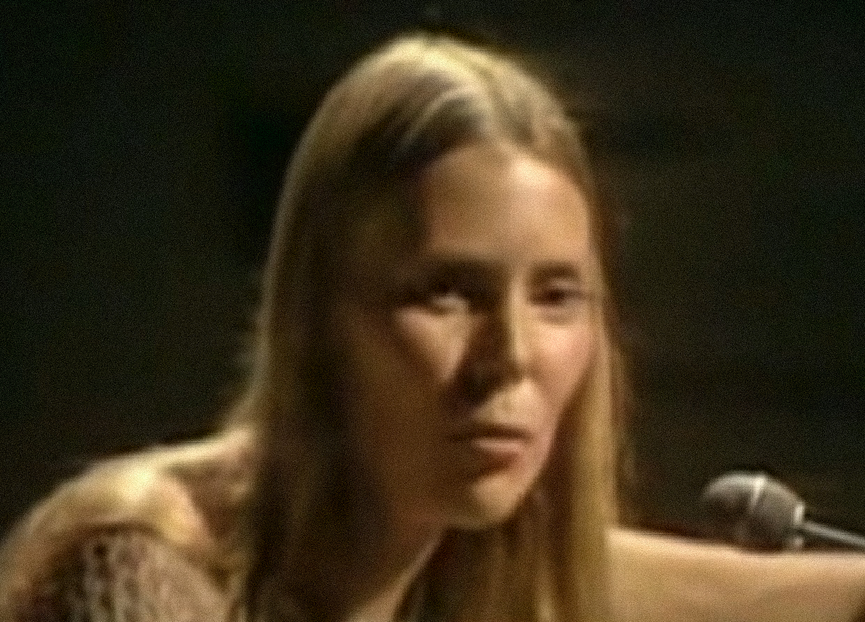 Screenshot: Joni Mitchell wearing brown shirt is looking at side - from Joni Mitchell: A Woman of Heart and Mind (2003)