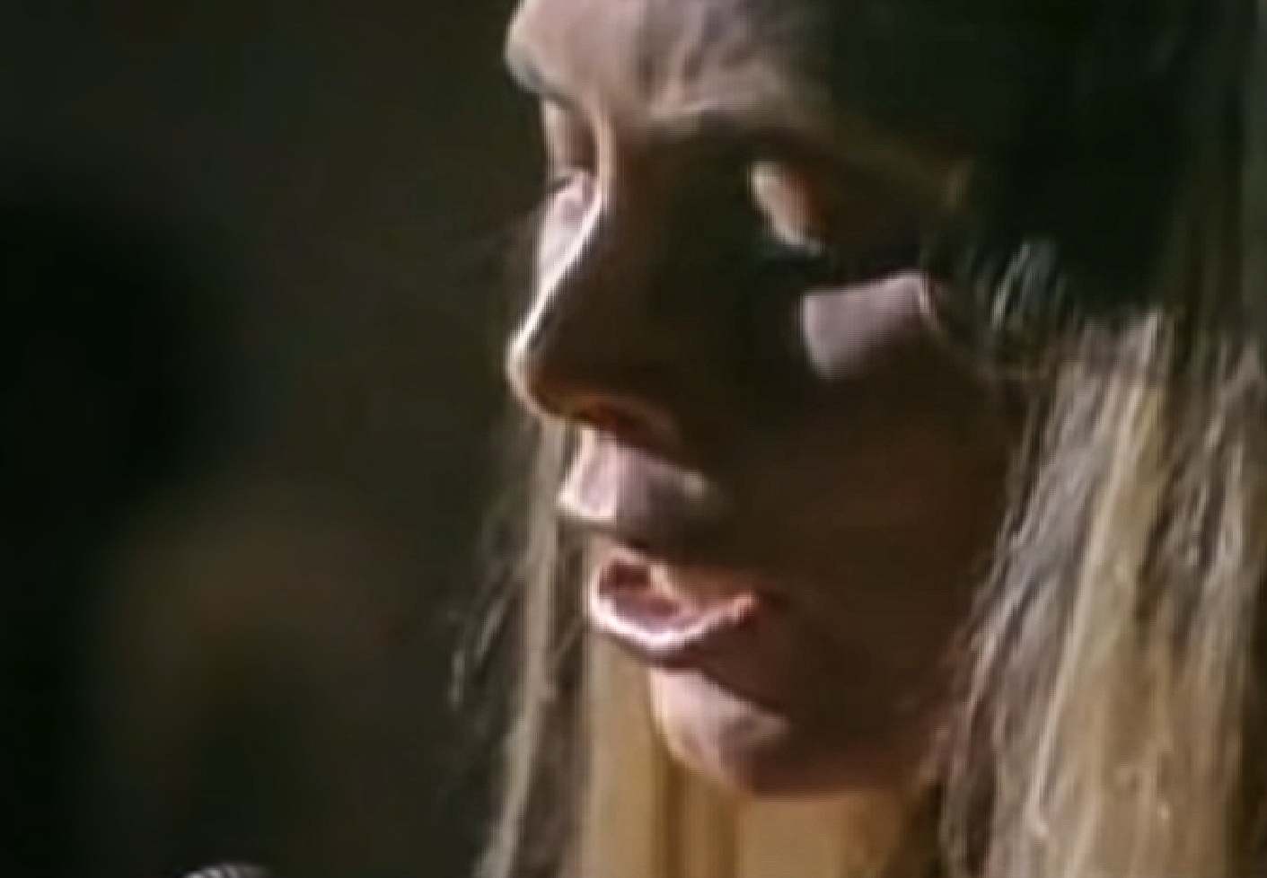 Screenshot: Joni Mitchell with long blonde hair is singing - from Joni Mitchell: A Woman of Heart and Mind (2003)