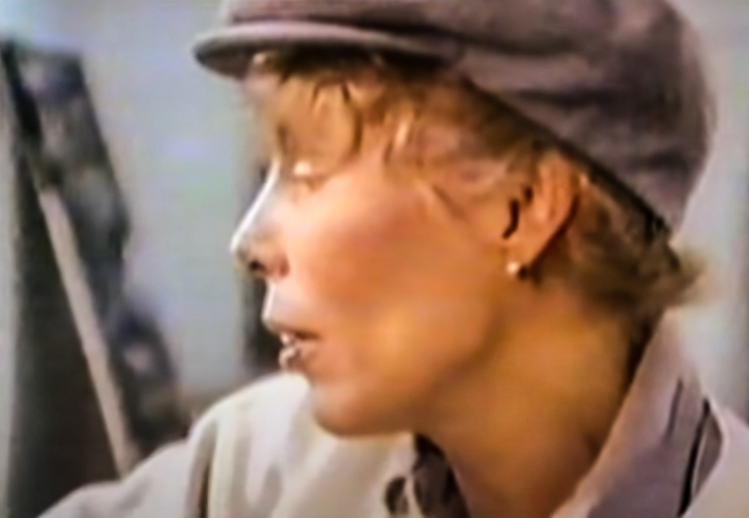 Screenshot: Joni Mitchell wearing grey hat is looking at front - from Joni Mitchell: A Woman of Heart and Mind (2003)