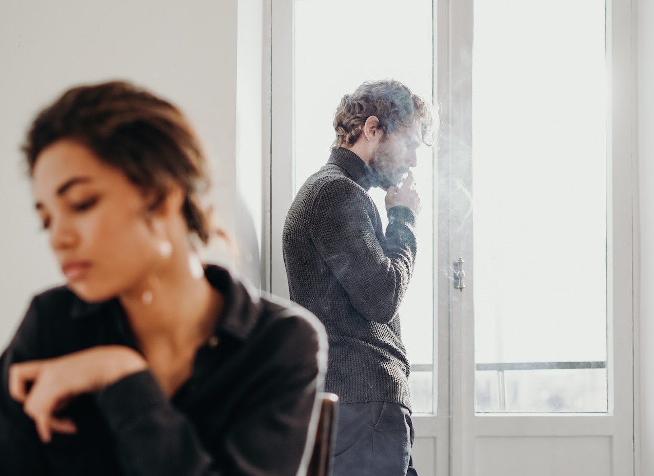 Young couple are seating in the room looking upset .