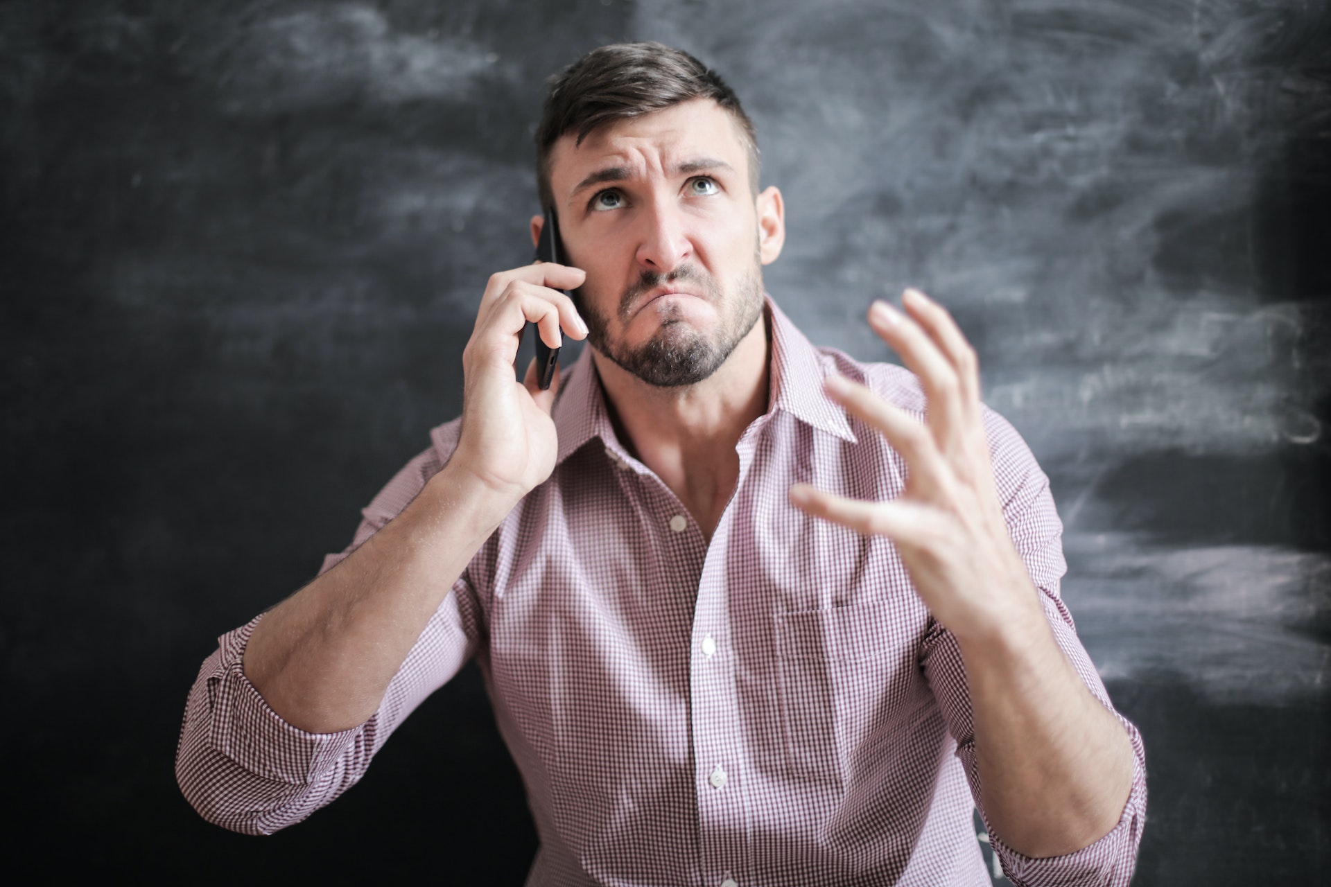 Angry man speaking on the phone in pink shirt