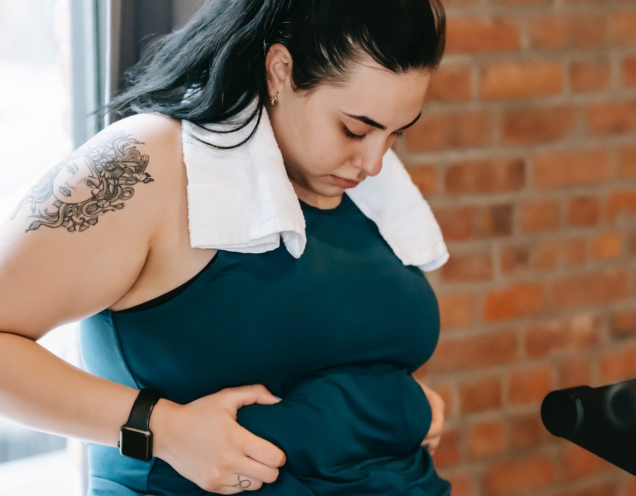 Plus size woman is holding fat fold on belly.