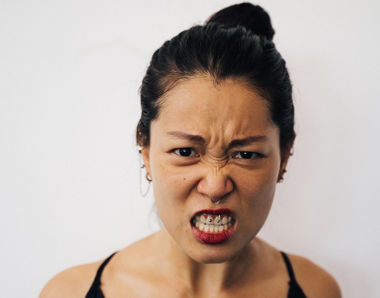 Angry woman is looking at camera on grey background.