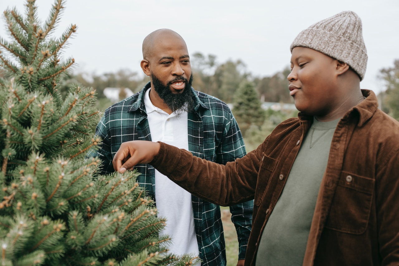Two people are talking outside ,standing by the Christmas tree.