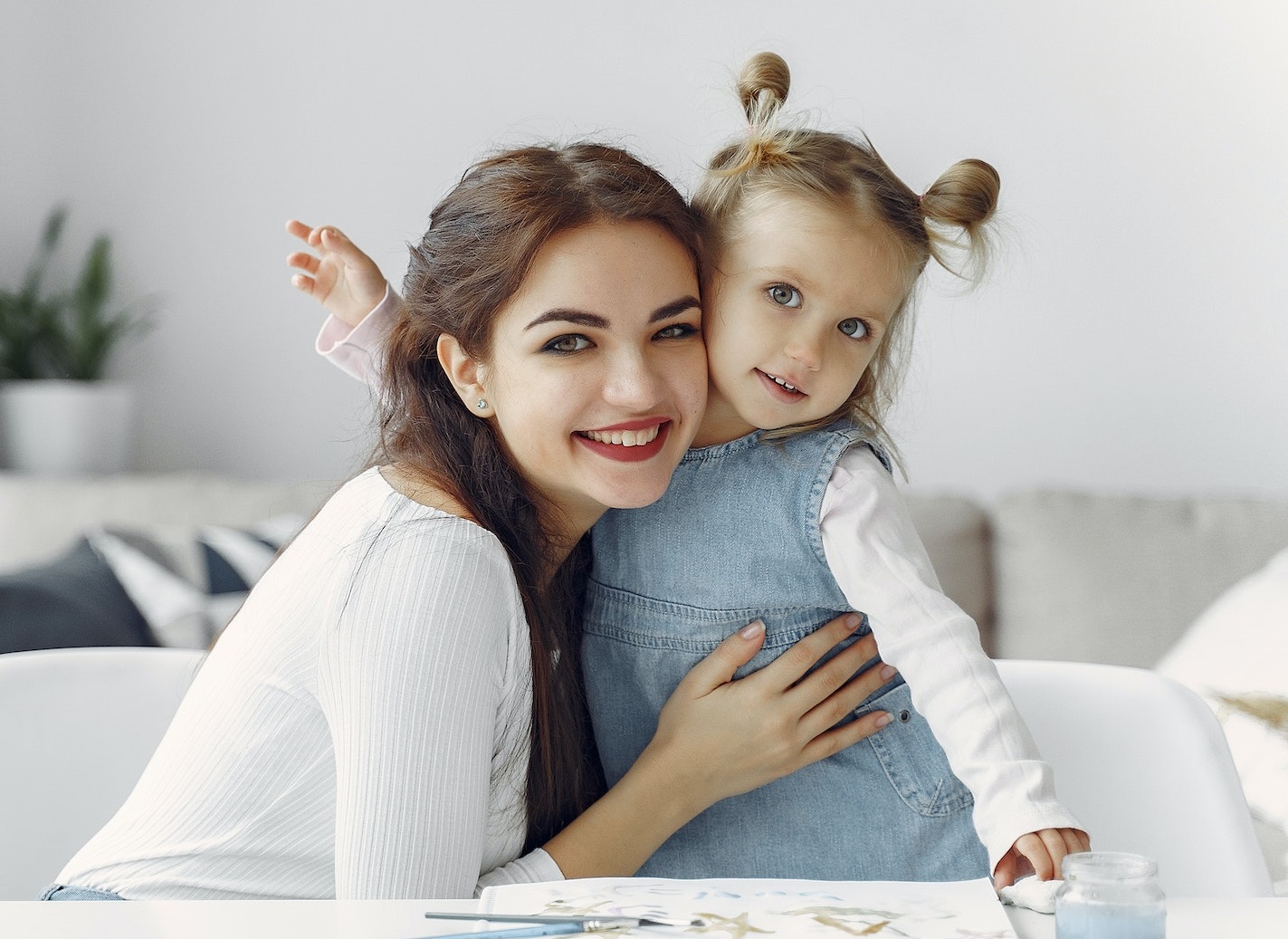 Young mother is holding her small daughter in her arms and smiling