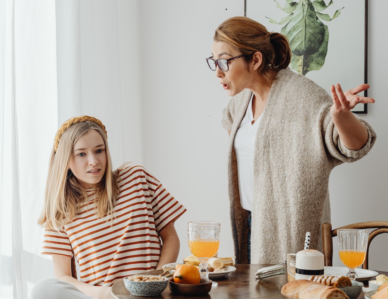 Woman is yelling to a girl seating on the table.