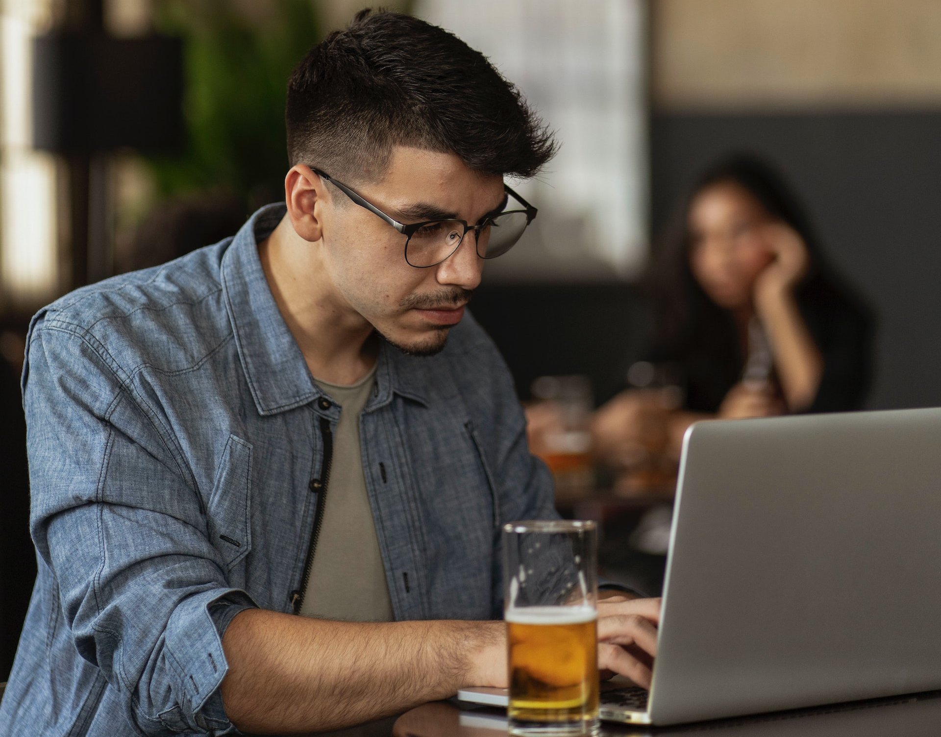 Man working on a laptop drinking beer
