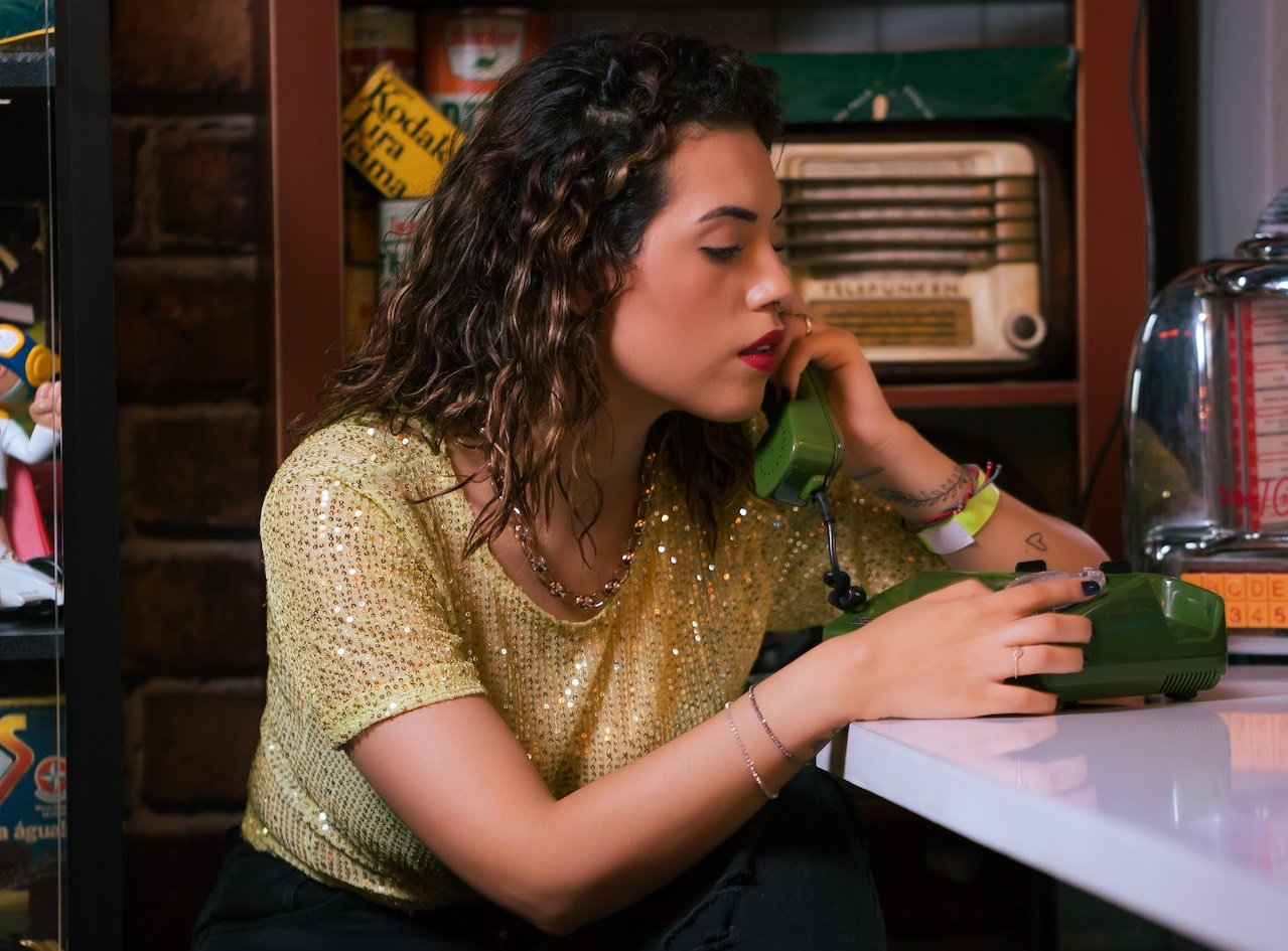 Young woman is talking on old green telephone.
