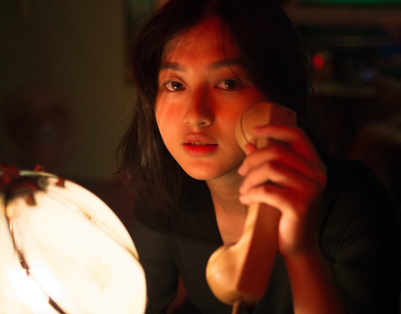 Woman holding a telephone in her hand in dark room.