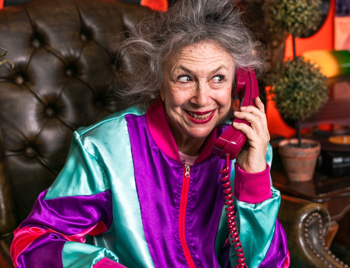 Woman is talking on the purple telephone and smiling.
