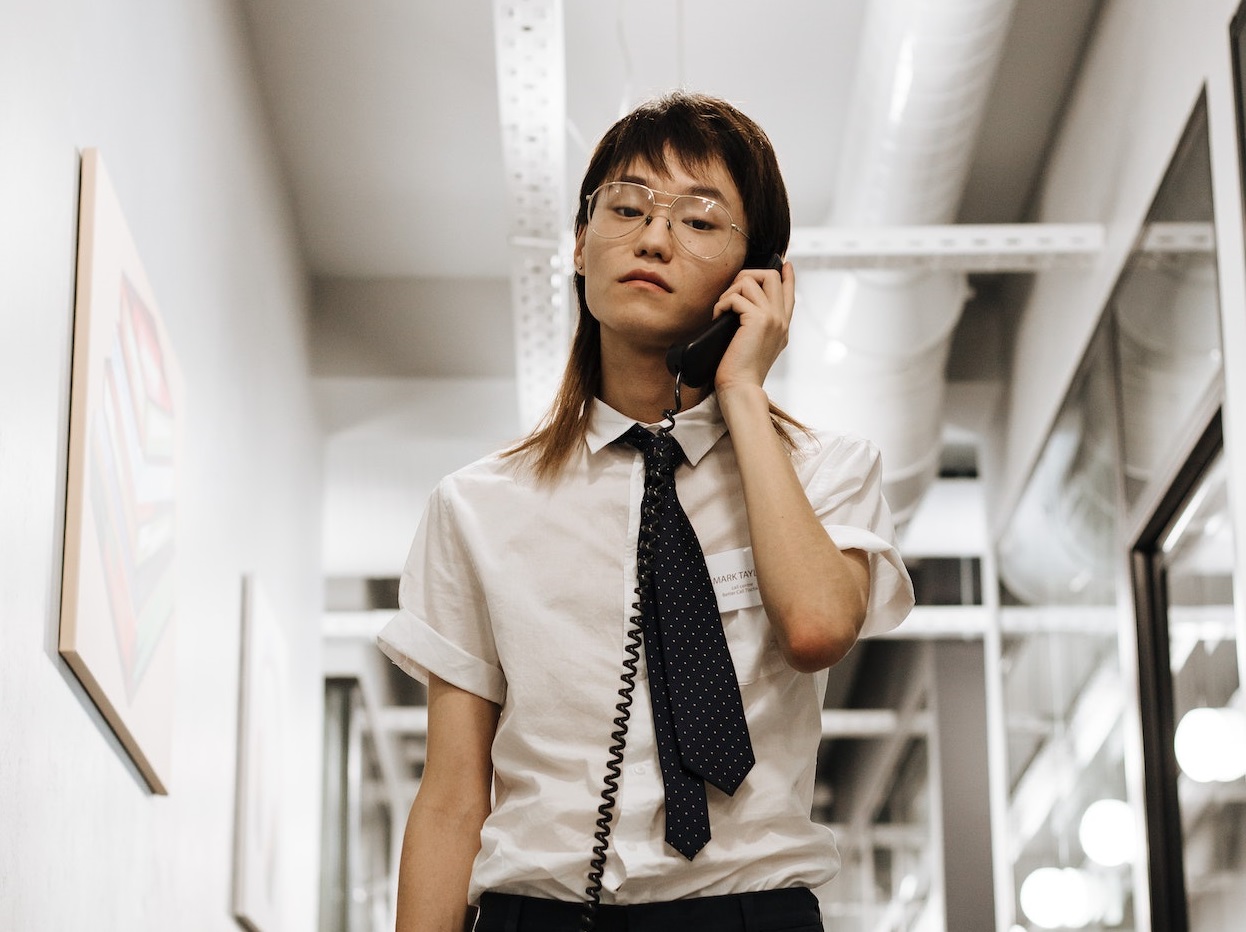 Asian young man with long hair is talking on telephone.