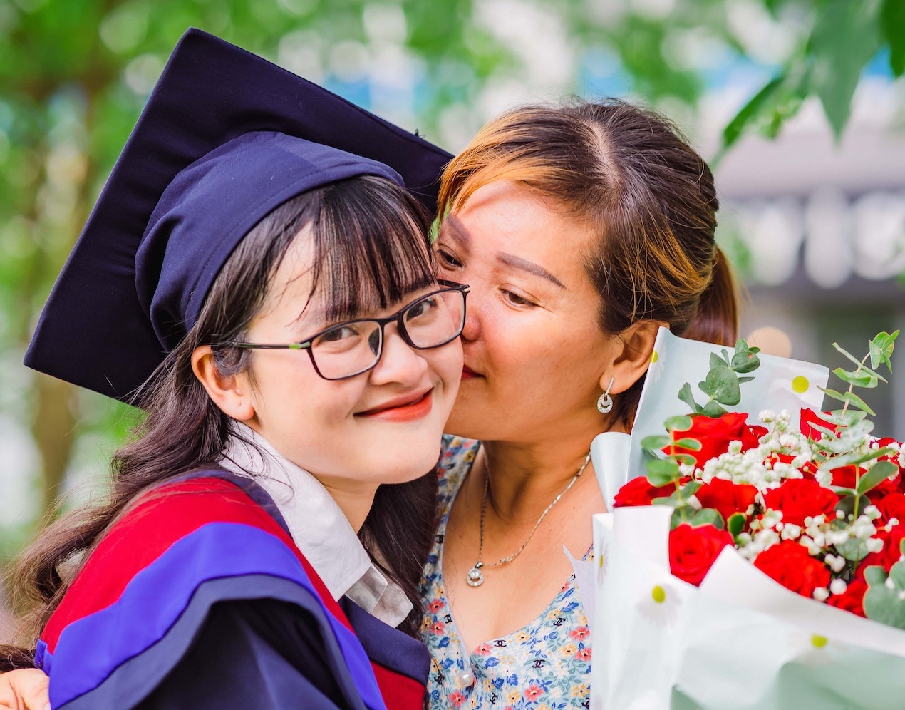 Mother is hugging her graduate daughter ,looking happy.