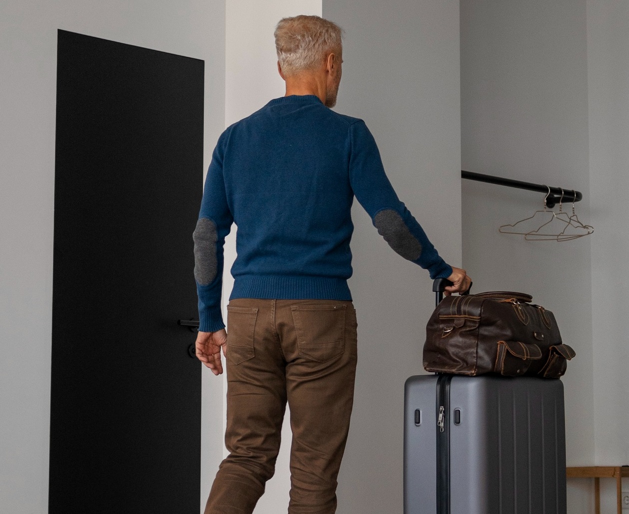 Man is leaving the house with suitcases.